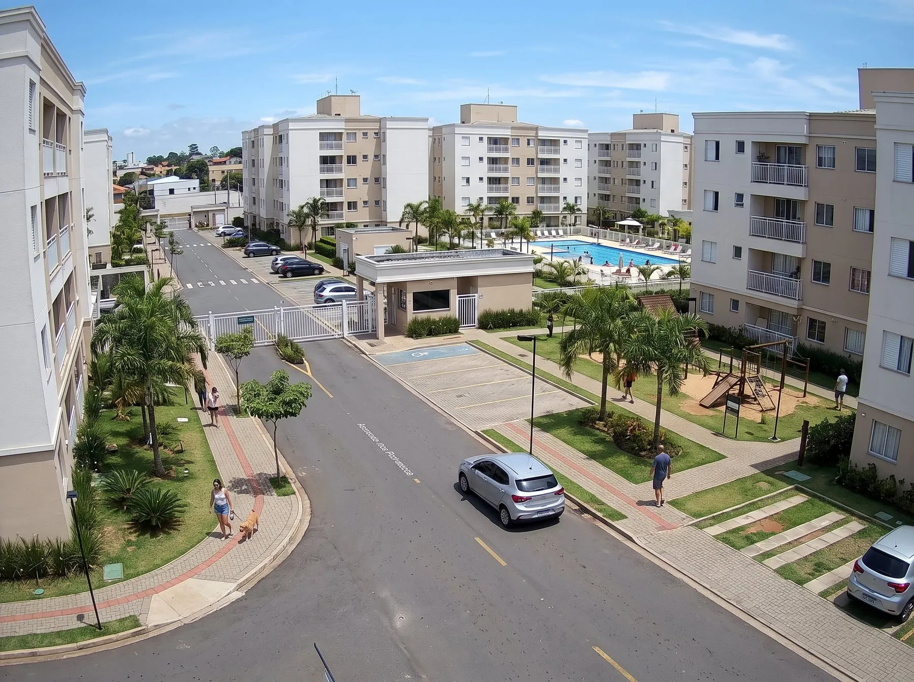 Câmera no alto de um condomínio mostrando a portaria, a rua interna, a piscina e o playground
